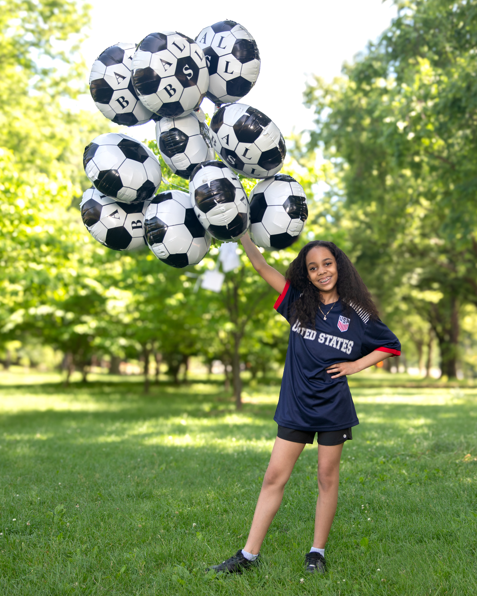 Young USA-jersey fan with a huge cluster of soccer-ball foil balloons