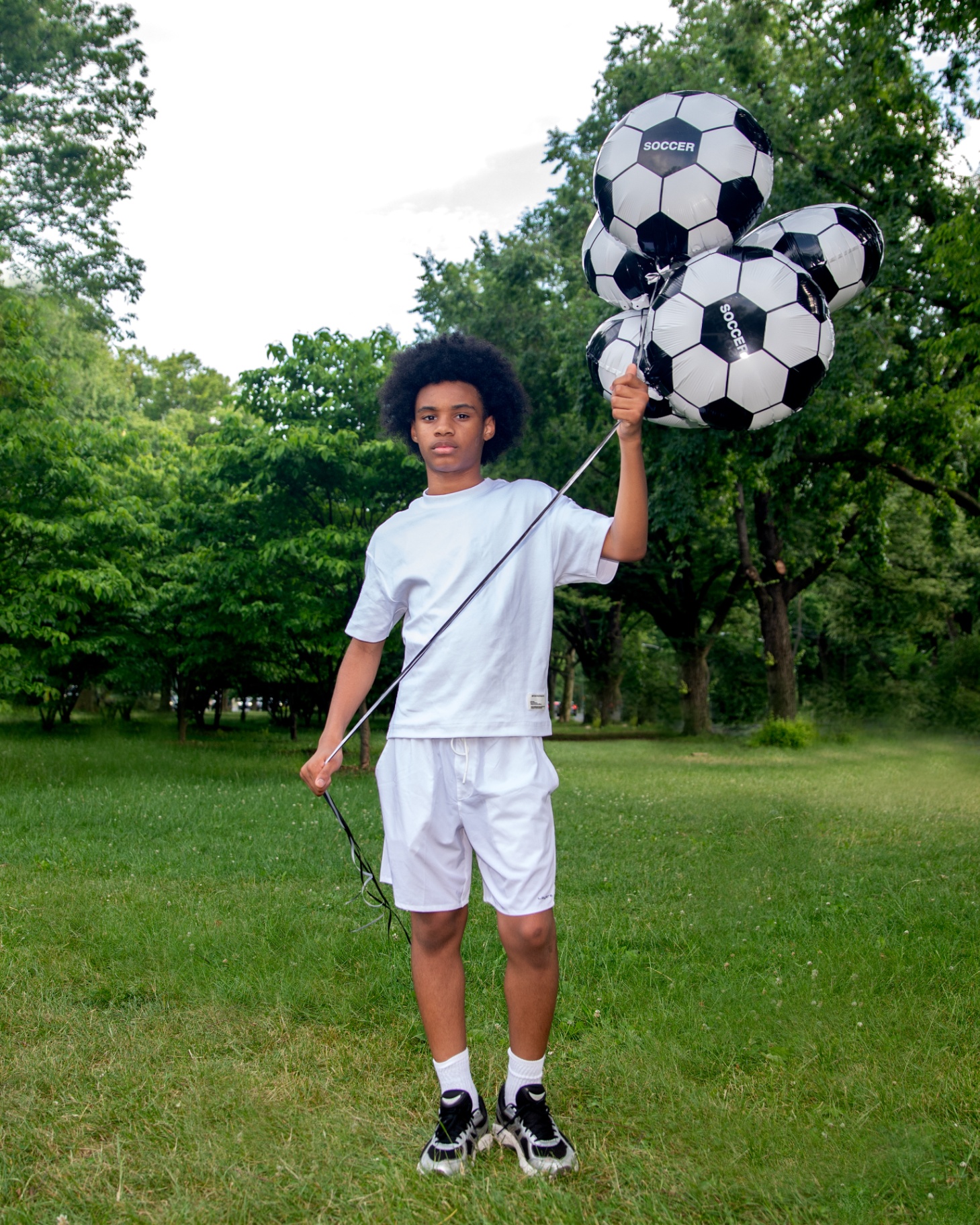Boy holding a tight cluster of SOCCER balloons